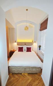a bedroom with a white bed with two red pillows at Deluxe Vintage Chic Apartment - Kazimierz Old Town in Kraków
