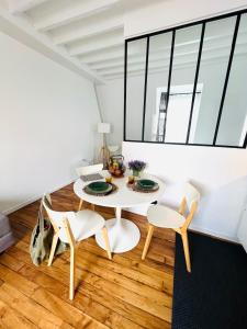 Un comedor blanco con una mesa y sillas. en Welcome to Montmartre, en París