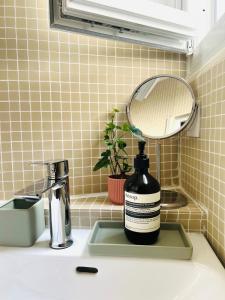 Una botella de jabón sobre un lavabo junto a un espejo. en Welcome to Montmartre, en París