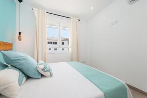 Un dormitorio con una cama con almohadas azules y una ventana. en Canyamel A, en Canyamel