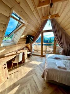 a bedroom with a bed and a desk and windows at Zakątek Zakopane in Zakopane