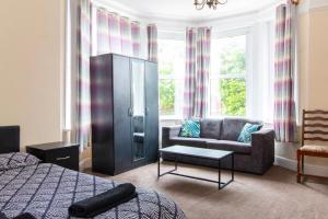 a bedroom with a couch and a chair in front of a window at Thornbury Guest House Room 1 in Southampton