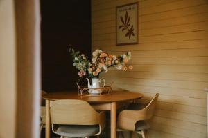 a wooden table with a vase of flowers on it at Tiny House Sage - ElysianFields in Sadu