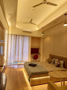 a bedroom with a bed and a table and a window at Gaur City Mall Homestay in Ghaziabad
