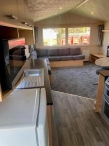 a kitchen and living room with a couch and a table at Lovely 8 Berth Caravan For Hire In Essex At Naze Marine Park Ref 17181P in Walton-on-the-Naze