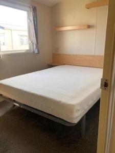 a large bed in a small room with a window at Lovely 8 Berth Caravan For Hire In Essex At Naze Marine Park Ref 17181P in Walton-on-the-Naze
