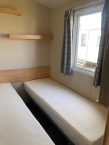 a small room with a bed and a window at Lovely 8 Berth Caravan For Hire In Essex At Naze Marine Park Ref 17181P in Walton-on-the-Naze