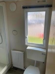 a bathroom with a toilet and a window at Lovely 8 Berth Caravan For Hire In Essex At Naze Marine Park Ref 17181P in Walton-on-the-Naze +12 photos