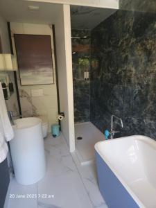 a bathroom with a tub and a toilet and a sink at Lazy Olives in Tongeren