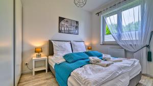 a bedroom with a bed with blue sheets and a window at Apartament Pod Brzozami - 5D Apartments in Świeradów-Zdrój