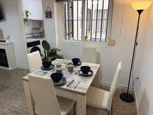 a dining room table with white chairs and a table with dishes on it at Santelmo,16 in Málaga