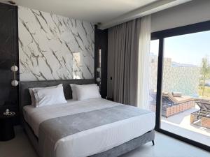a bedroom with a large bed and a large window at Celeste Luxury Villas in Lardos +48 photos