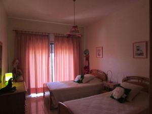 a bedroom with two beds and a window with pink curtains at Quinta das Palmeiras - T2 in Porches