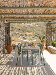 a table and chairs under a wooden pergola at Serifos Dream Houses near the sea in Ganema
