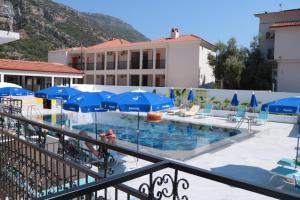 a swimming pool with blue umbrellas and chairs at Taner Otel in Oludeniz