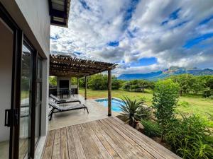 a house with a wooden deck and a swimming pool at 24 Degrees South Country Estate in Hoedspruit