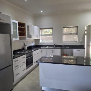 Una cocina con gabinetes blancos y encimeras negras. en Eshowe Hills The 19th, en Eshowe