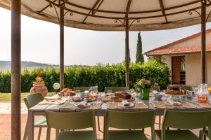 a table set for a meal under an umbrella at CASALE TEATRO 10, Emma Villas in Laiatico