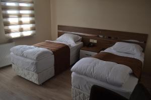 una camera d'albergo con due letti e un pouf di Divrigi Kosk Hotel a Divriği