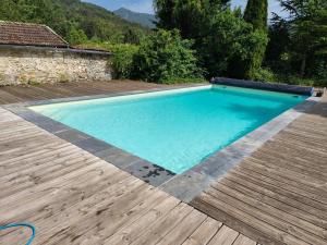 BoulcGîtes au Moulin de Ravel的院子里有带木甲板的游泳池