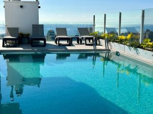 Una piscina con sillas y vista a la ciudad. en Apartamentos Bruja, en Santa Cruz de Tenerife