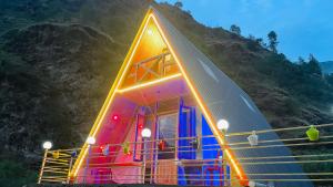 a house with lights on the side of a mountain at River Nest Cottage Shangarh in Sainj