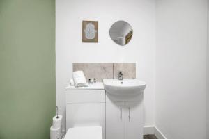 a white bathroom with a sink and a toilet at Spacious & Stylish - Free Parking - Fast Wifi in Cardiff
