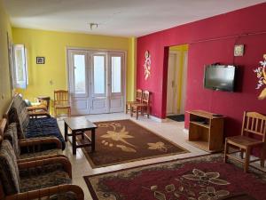 a living room with yellow and red walls and a tv at Chalet two rooms on the North Coast Misr lel tameer village in Qaryat Shurūq