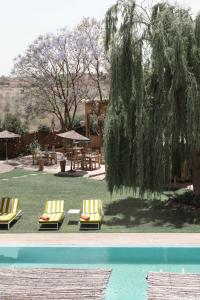 two chairs and a table and a tree next to a pool at Jnan Lotf Marrakech - Le Jardin de la Bienveillance in Marrakech