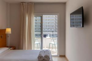 a hotel room with a bed and a balcony at Bay Hotel in Roses