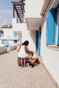 a woman and a girl with luggage on a building at Anima Jesolo - Drago Village - Family Apartments - City Center, Pool & Garden, Beach Umbrella Included, 2 Parking Spaces in Lido di Jesolo