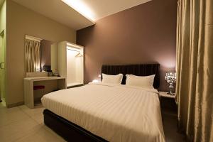 - une chambre avec un grand lit et des draps blancs dans l'établissement Seven Hotel, à Putatan