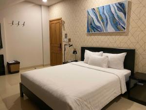 a bedroom with a large white bed with a painting on the wall at THE STAR HOTEL 2 - Phú Mỹ Hưng, Hồ Chí Minh in Ho Chi Minh City