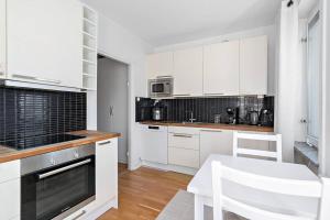 a kitchen with white cabinets and a table and a chair at Apartament u Ann in Grzędzice