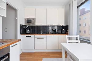 a white kitchen with white cabinets and a table at Apartament u Ann in Grzędzice