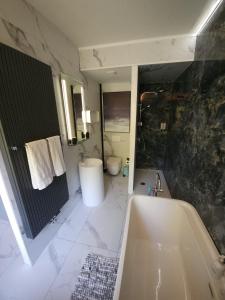 a bathroom with a tub and a toilet and a sink at Lazy Olives in Tongeren