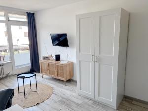 a living room with a tv and a desk with a chair at Apartment Mövenkoje für 1-2 Personen mit Pool in Dahme +17 photos