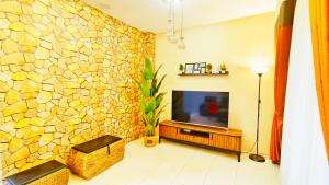 a living room with a stone wall and a television at Homestay Bunga Kertas Jitra in Jitra