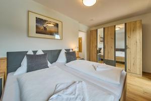 a bedroom with a large bed with white sheets at Platzhirsch Rooms - B&B - SELF CHECK-IN in Piesendorf