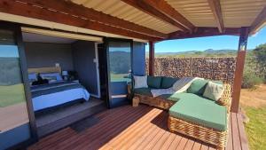 eine Veranda mit einem Bett und einer Couch auf einer Terrasse in der Unterkunft Lovedale Farm Getaway in Jansenville