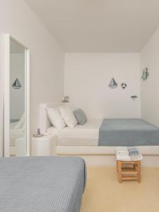 a white bedroom with two beds and a mirror at Serifos Dream Houses near the sea in Ganema