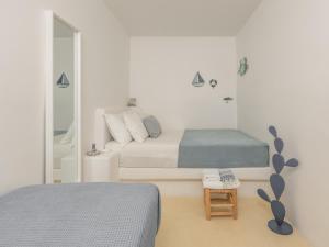 ein weißes Schlafzimmer mit zwei Betten und einem Spiegel in der Unterkunft Serifos Dream Houses near the sea in Ganema