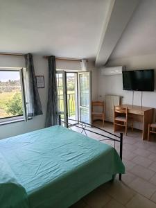 a bedroom with a bed and a desk and a television at Bed and Breakfast L' Aranciera in Corigliano Calabro