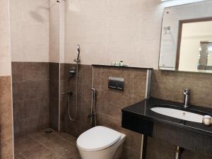 un bagno con un water, un lavandino e uno specchio di A and M Rooms and Residences a Chennai