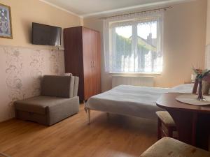 a bedroom with a bed and a chair and a table at Pokoje Gościnne DANA in Łeba