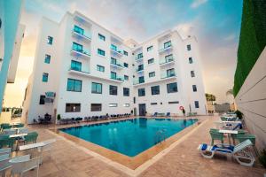 a hotel with a swimming pool in front of a building at Rafiny Hôtel in Ksar el Kebir