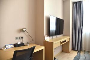 南京Nanjing Grand View Hotel的酒店房间配有书桌、电视和椅子 更多1张照片
