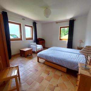 a bedroom with a large bed and two windows at Chalet dans les alpages de Savoie in Villard-sur-Doron +11 photos