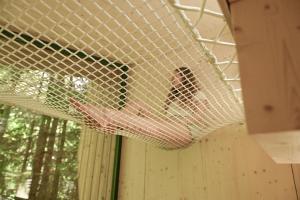 a person in a hammock in a batting cage at Green Tiny Village Harz - Tiny House Nook 20 in Osterode +44 photos