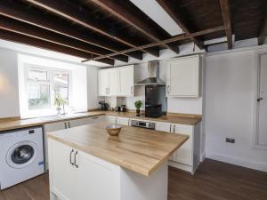 a kitchen with white cabinets and a wooden counter top at Hemdin Cottage in Pickering